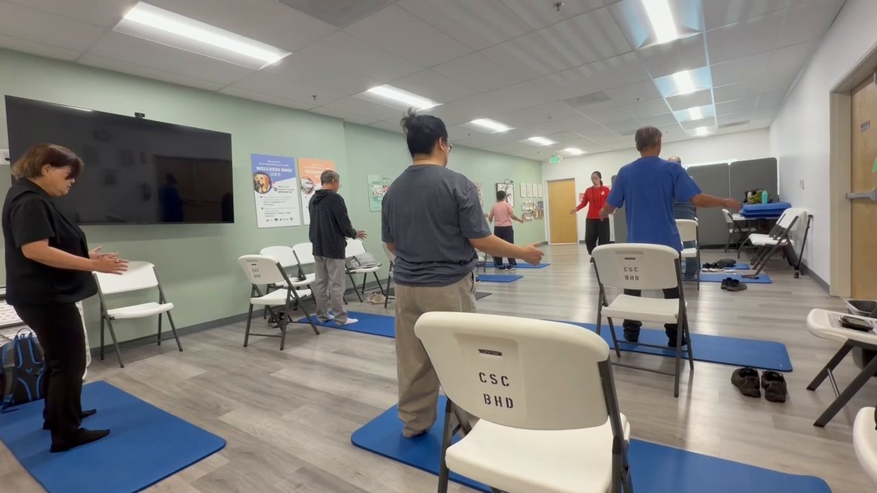 A weekly community class in session in Monterey Park, practicing on mats, seen from the back of the room
